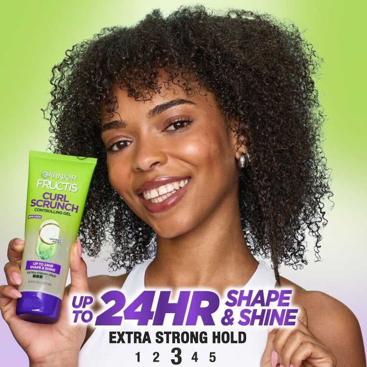 Woman smiling, holding Garnier Fructis Curl Scrunch Gel, 'Up to 24HR Shape & Shine' text.